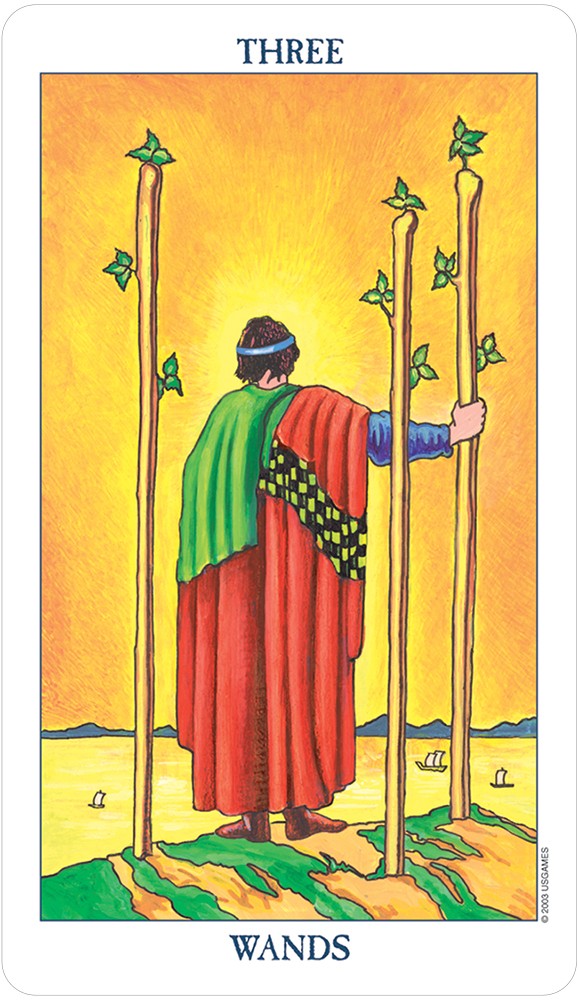 card labeled "three of wands." depicts a man in a red robe chased with black and yellow checkers, holding three staffs.